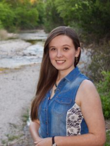 Picture of Destiny smiling in front of a small river bed.