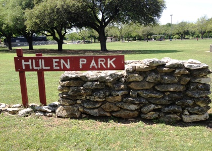 The red wooden Hulen Park sign with stone formation.